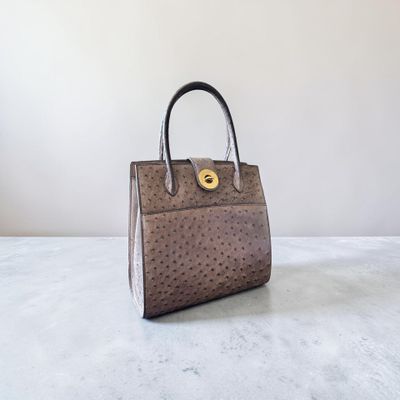 un sac à main en autruche marron posé sur une table blanche