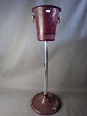 a red bucket on a metal stand with a handle