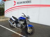 une moto bleue garée sur un parking, près d'un mur