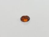 an orange sapphire stone on a white surface