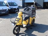 a yellow scooter parked in a parking lot with other vehicles in the background