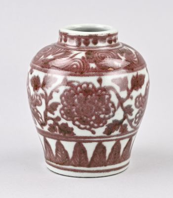 un vase rouge et blanc posé sur une surface blanche