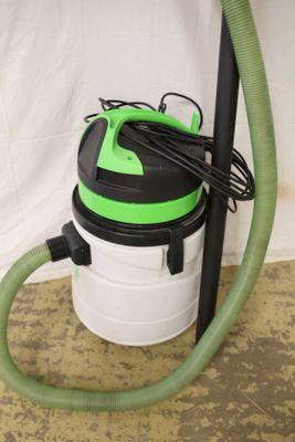 a green and white vacuum and a green hose on the floor