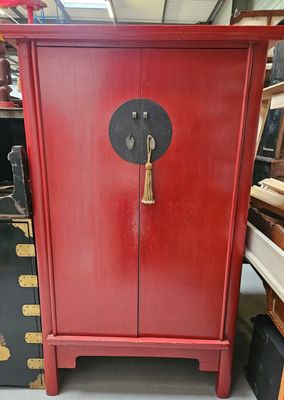 une armoire rouge avec une porte noire et une poignée dorée