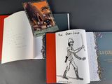 three books on a table with a drawing of a man holding a sword and a drawing of a man holding a sword