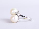 a close up of a pearl and diamond ring on a white surface