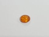 an orange sapphire stone on a white surface