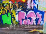 a man sitting on the ground with a skateboard in front of a graffiti covered wall