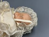 a small doll in a white dress with a ribbon around it
