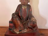 une statue représentant un homme assis sur une table en bois