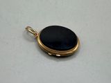 a gold locke with a black stone in it on a white surface