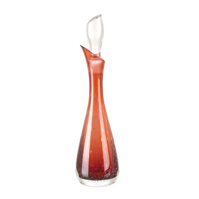 une carafe en verre orange, au col incurvé et au pied blanc