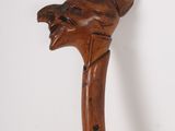 an old wooden walking stick with a face carved into it