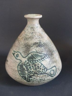 un petit vase avec un oiseau sur une table