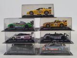 six different model cars in display cases on a white surface