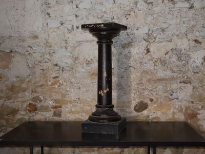 a black table with a candle on it in front of a brick wall