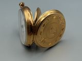 a gold pocket watch sitting on a white surface