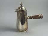 une cafetière ancienne en argent avec une poignée en bois sur fond blanc