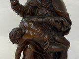 statue of a woman sitting on a man ' s lap holding a baby