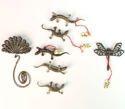 de nombreux petits lézards et libellules en métal sur une surface blanche
