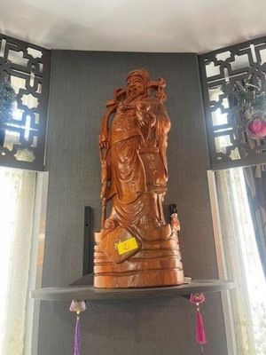une statue en bois représentant une personne, posée sur une étagère dans un coin de la pièce