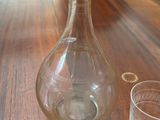 a glass vase on a table with glasses on it