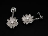 paire de boucles d'oreilles en forme de fleurs en argent avec une chaîne, sur fond noir