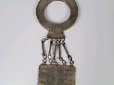 a metal object hanging from a chain on a white surface