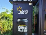 un panneau sur lequel est écrit « Just Queen » et une poubelle devant une autre poubelle