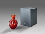 a red vase sitting next to a box on a table