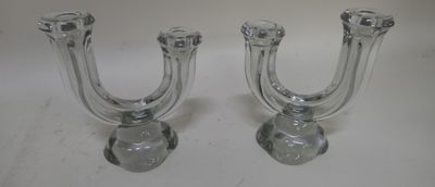 une paire de bougeoirs en verre transparent posés sur une surface blanche