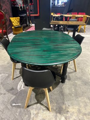 green round dining table with four black chairs and a red chair