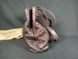 brown leather handbag on a black background with a yellow cloth