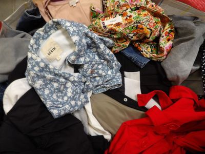 une valise pleine de vêtements et un chapeau posé par terre