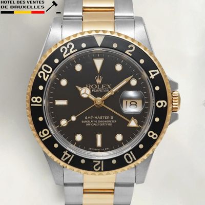 a rolex watch with a black dial on a gold bracelet