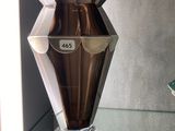 un vase en argent posé sur une étagère en verre dans une pièce