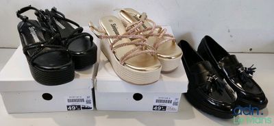 trois paires de chaussures noires et dorées sont posées sur une boîte blanche