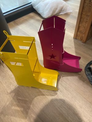 Deux paires de bottes de cow-boy sont posées par terre à côté d'une paire de chaussures.