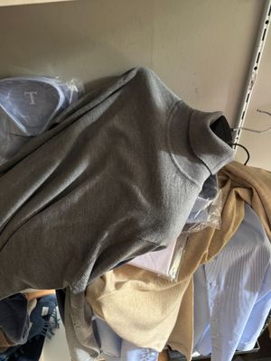 une pile de vêtements suspendus à un portant dans un placard