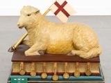 a statue of a sheep with a flag on top of a book