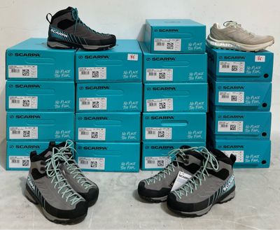 Plusieurs paires de chaussures sont empilées sur une pile de cartons