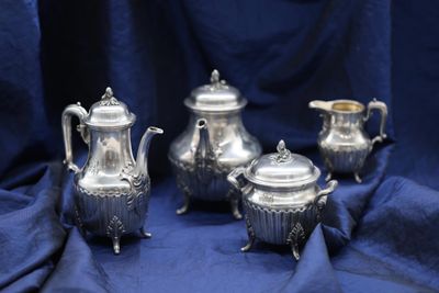 four pieces of silver tea and coffee set on a blue cloth