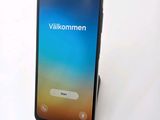 the back of a black phone with a blue screen on a white surface