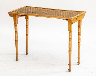 une petite table avec un plateau tressé et des pieds en bois