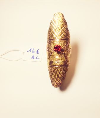 a small gold bug with a red bead on it