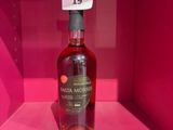 une bouteille d'alcool vide posée sur une étagère rose, dans une boîte rose