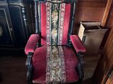 une chaise rouge et noire dans une pièce où est accroché un tableau