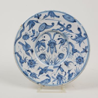 blue and white plate with birds and flowers on it on a stand