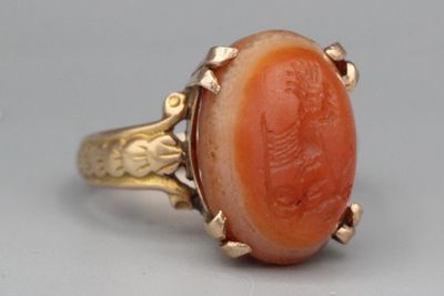 une image représentant une bague en or sertie d'un corail sculpté