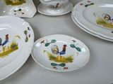 several plates and bowls with roosters painted on them on a table